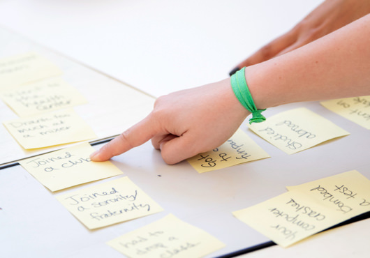 Hands pointing at sticky notes on a project board