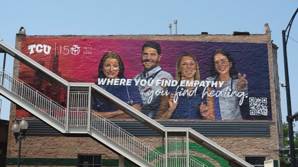 Large TCU 150 mural on the side of a brick building, featuring four Chicago-area TCU alumni working in medicine