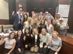 Class gathers after a 10-hour debate, smiling and giving the Go Frogs hand sign