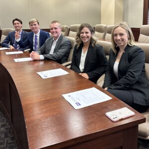 One row of students, seated in the Debate Chamber, wearing business attire