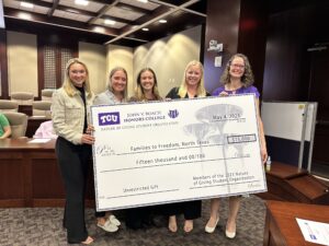 Five students hold up one of the large display checks