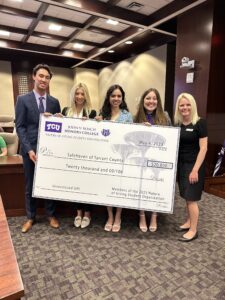 Another group of five students hold up a large display check