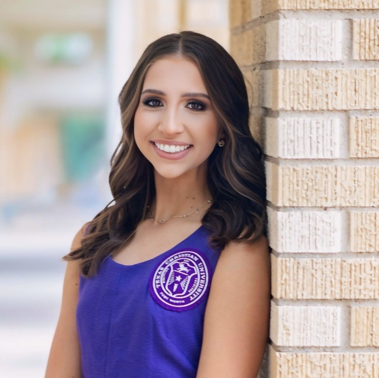Student Macy Bayer posing for a headshot wearing purple top with Texas Christian University patch
