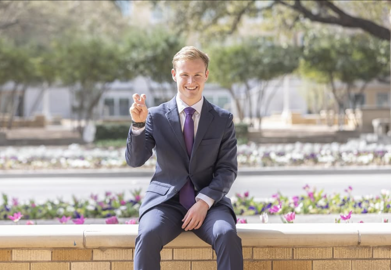 Student Titus Fagan posing for a picture outisde holding up a 'Go Frogs' hand sign